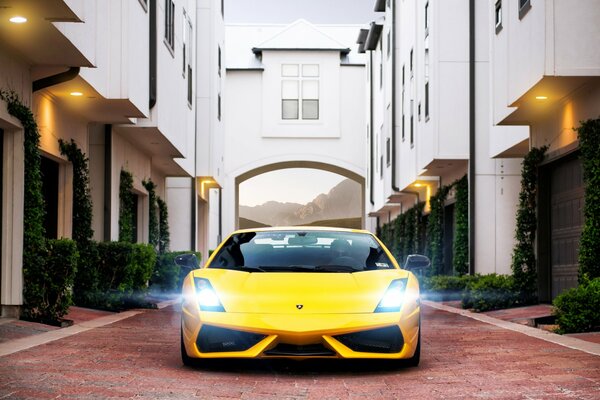 Lamborghini amarillo en adoquines en el patio de la casa