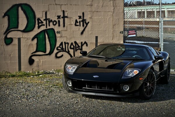 A black Ford poses against a painted brick wall