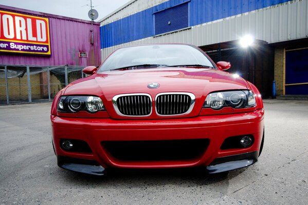 Voiture BMW rouge sur fond de cour et projecteur