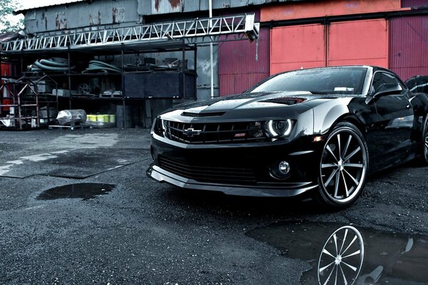 Black sports car on the background of garages and tires
