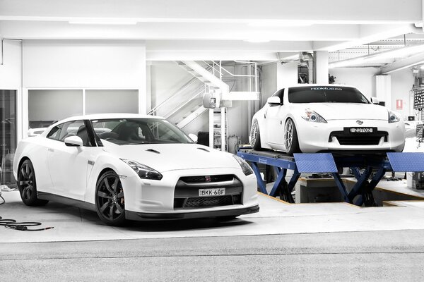 Two white Nissan cars in a white garage