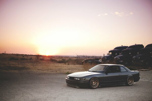 Nissan on the background of the setting sun and trucks