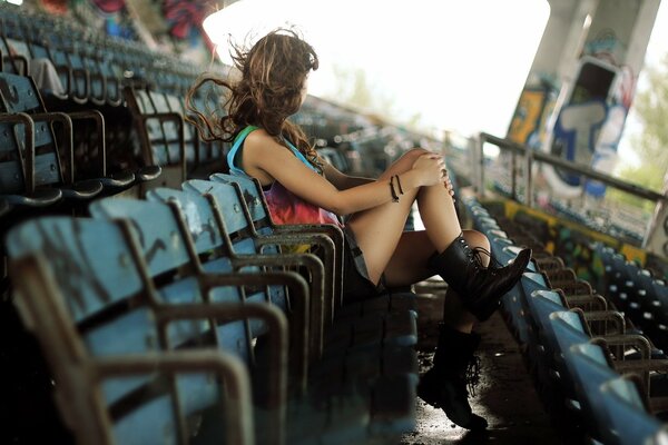 Fille réfléchie assis dans le stade