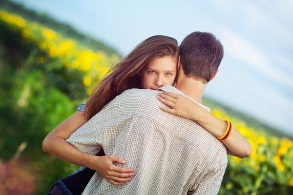 Gentle embrace of a blue-eyed girl in a field of flowers