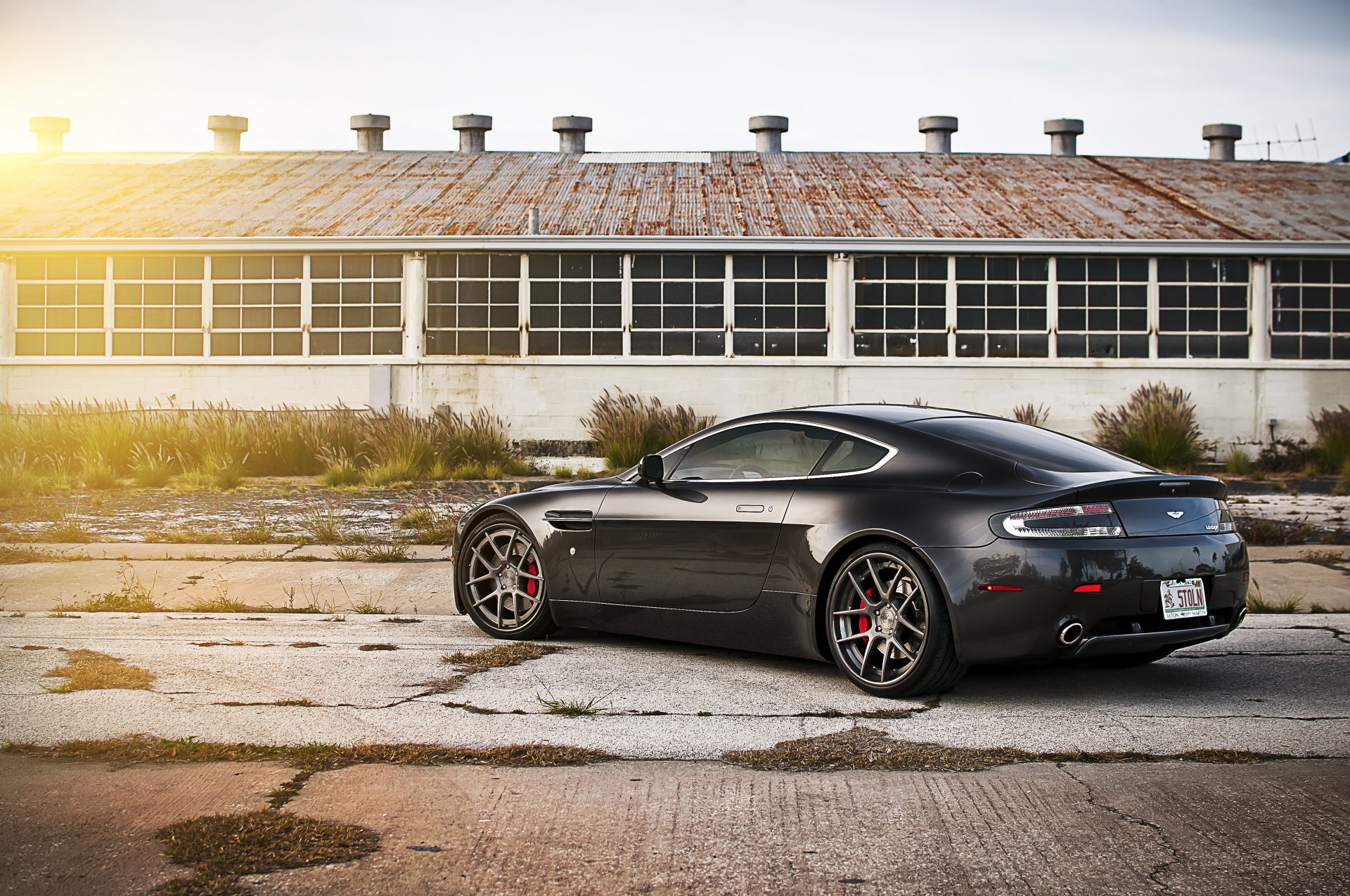 aston martin v8 vantage noir aston martin arrière hangar soleil éblouissement