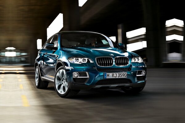 Blue bmw x6 rides through the night metropolis