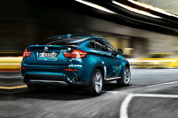 Un BMW X6 azul fresco corre por la carretera