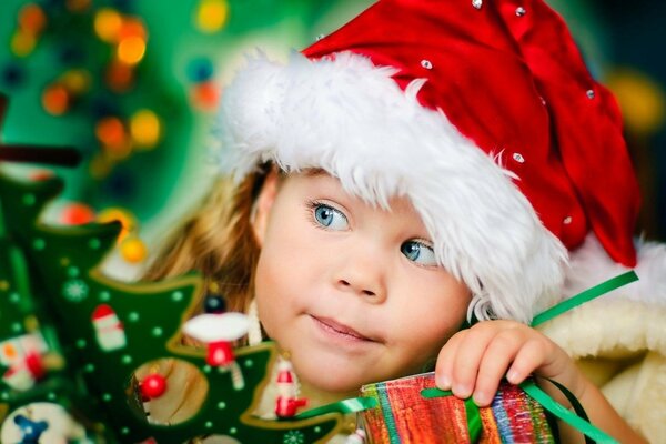 Cute girl in a hat under the Christmas tree