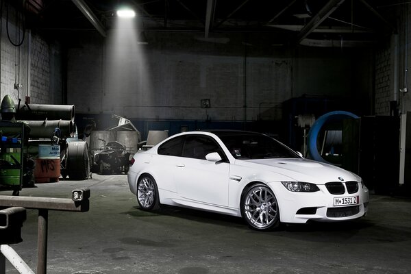 A white BMW is parked in a dark garage