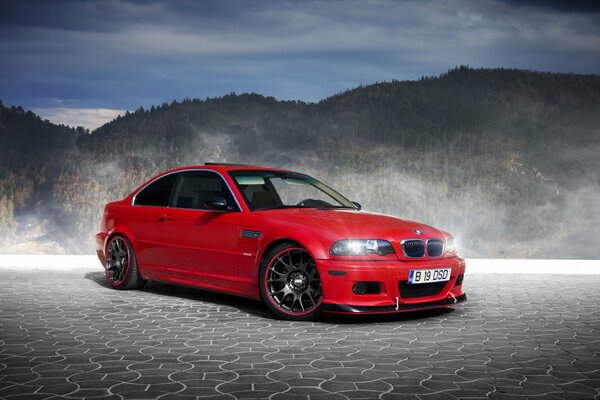 A red BMW stands against the backdrop of beautiful mountains