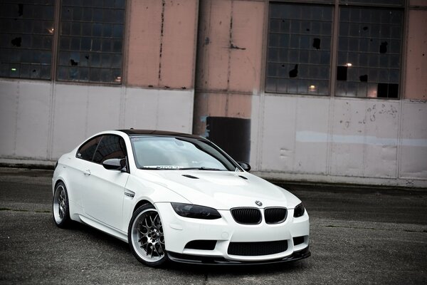 A beautiful white BMW with an abandoned building