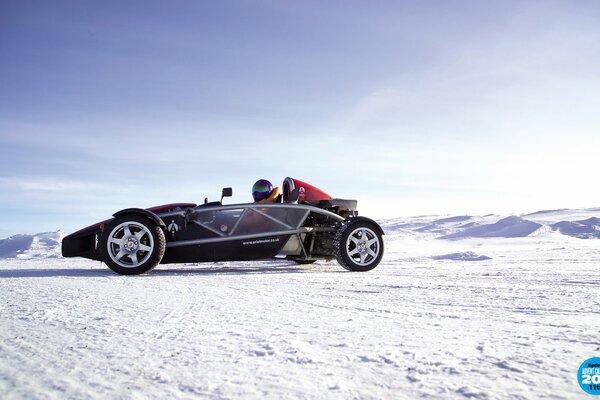 Supercar in the snowy desert with a man in a helmet