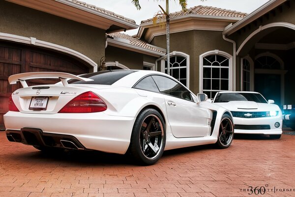 Two white cars in the yard of the house