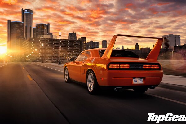 Orange sports car rides into the sunset