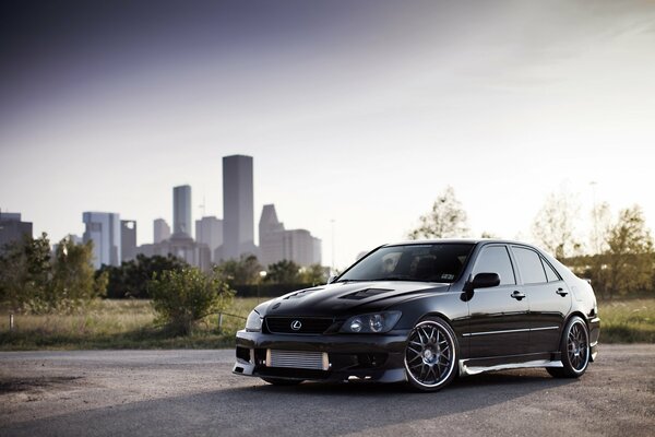 Black Lexus on the background of the city and sunset