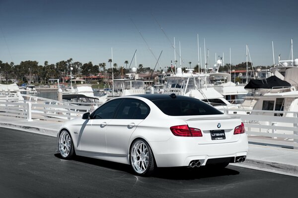 Luxury white bmw 5 series on the pier with yachts