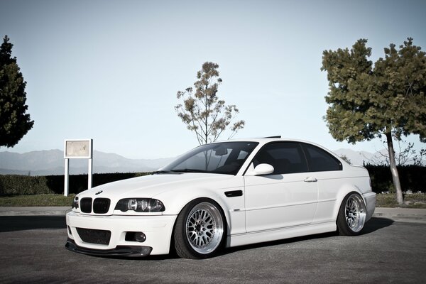 White BMW car on a background of blue sky and trees