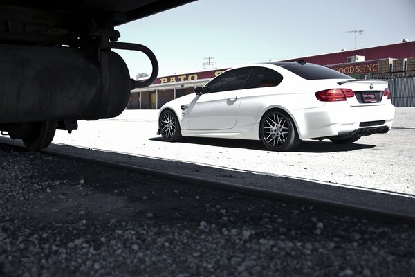 BMW blanco al lado de los rieles ferroviarios