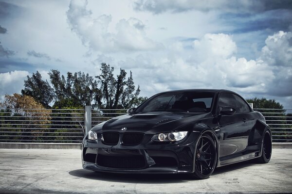 Black BMW against the sky and clouds