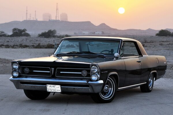 Voiture rétro Pontiac 1963 sur une route déserte sous le soleil