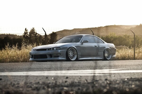 Nissan Silvia in grau auf Zaunhintergrund