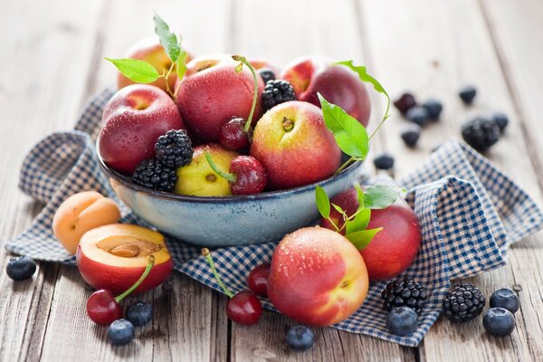 Lots of fruit on a plate and on a checkered napkin