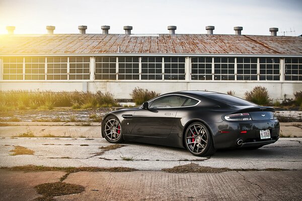 La parte posteriore di una Aston martin vantage nera sullo sfondo dell hangar