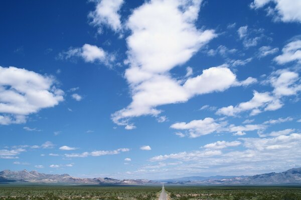 El camino que se adentra en la distancia que adorna el cielo en las nubes