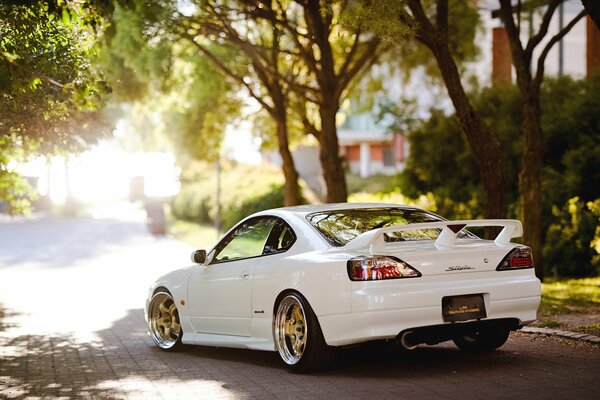 White sports Nissan on a shady street