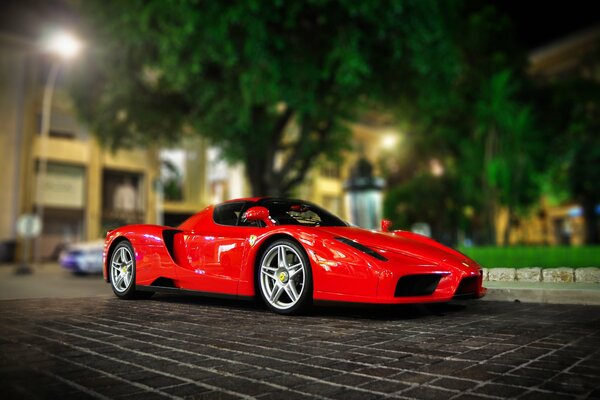 Leuchtend roter Ferrari auf dem Parkplatz vor dem Hintergrund der nächtlichen Stadt