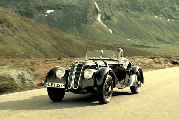 A rare car is driving on the road in the mountains