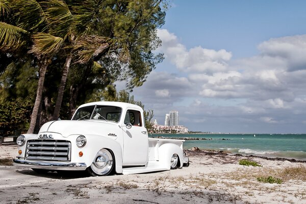 Weißer Retro GMC Pickup auf Strand und Palmen Hintergrund