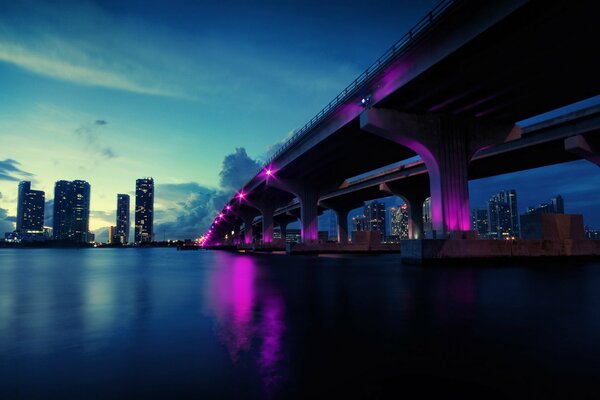 Puente de noche con luces de color carmesí sobre el agua