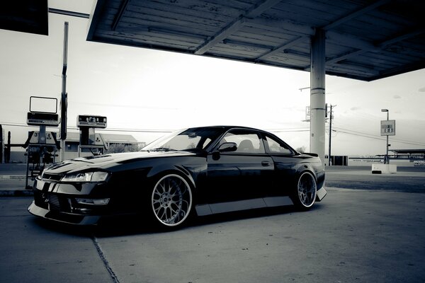 Noir Nissan Silvia S14 à la station-service rétro style