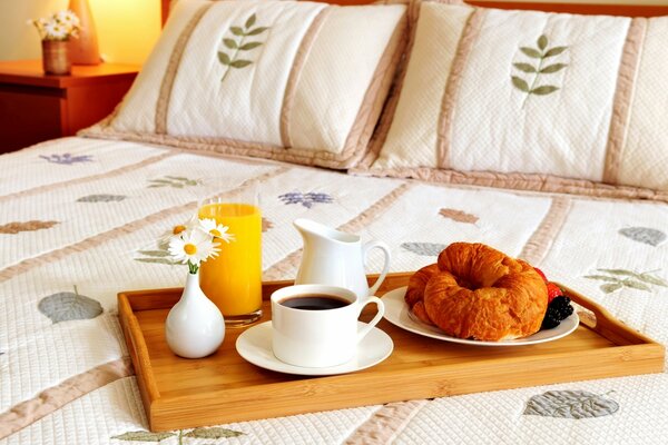 Plateau avec café et croissants et pâtisseries sur le lit