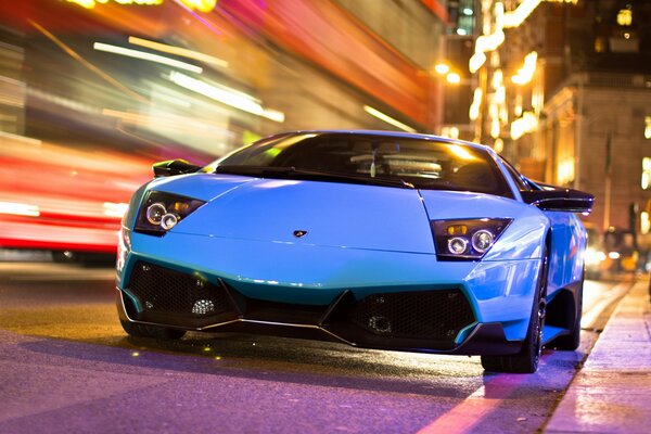 Une voiture de sport de couleur Indigo se précipite dans la ville de nuit