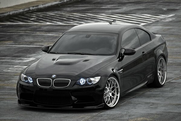 Black BMW with headlights on