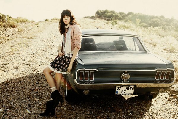 Morena chica se apoyó en un coche Mustang retro