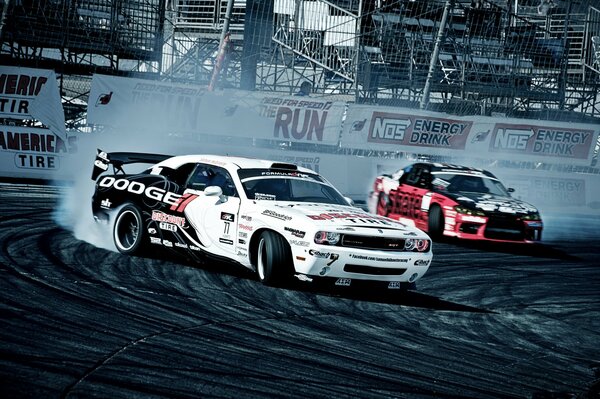Dodge challenger dodged with drift and smoke from nissan silvia in front of the stands at the competition