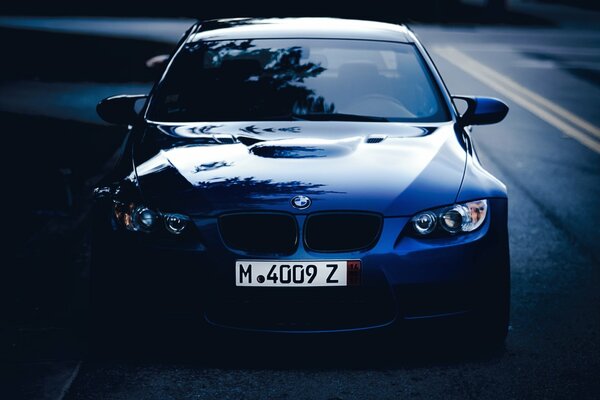 Blue BMW M3 parked on an open road against the night sky