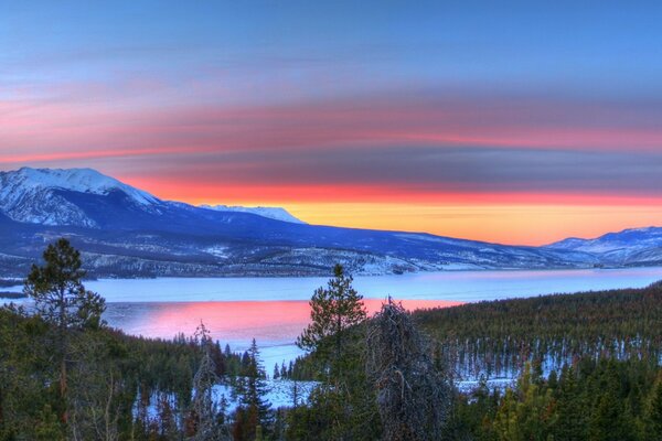 Zimowe jezioro z górami o zachodzie słońca