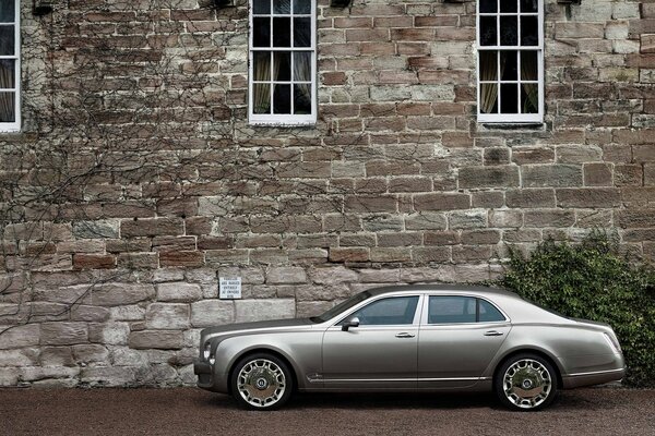 Srebrny Bentley na tle kamiennej ściany domu