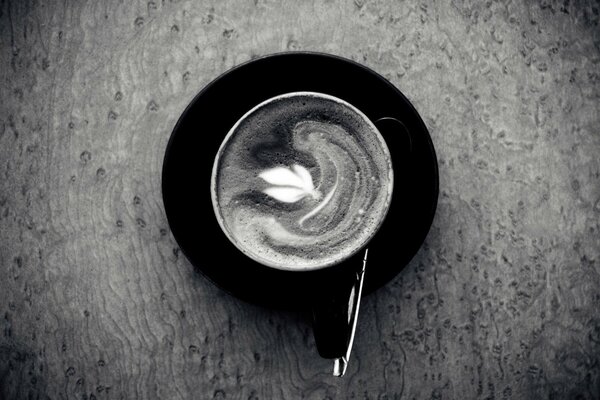 Black and white photo of a cup of coffee with a saucer and a spoon