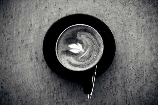 Foto in bianco e nero di una tazza di caffè con piattino e cucchiaio