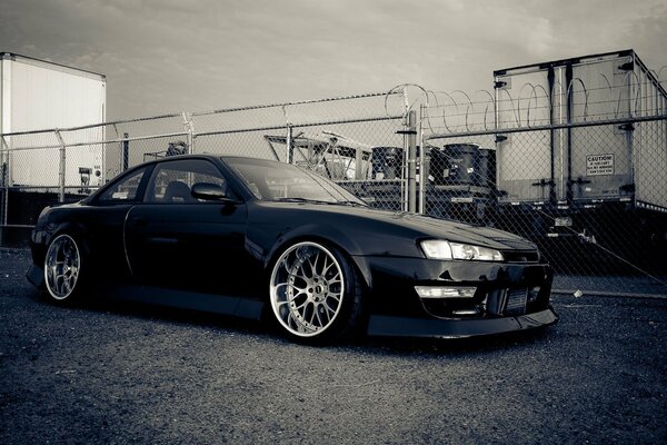 A black tuned Nissan on the background of a closed territory