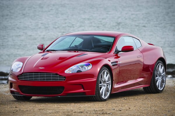 Aston Martin rojo en la playa de arena