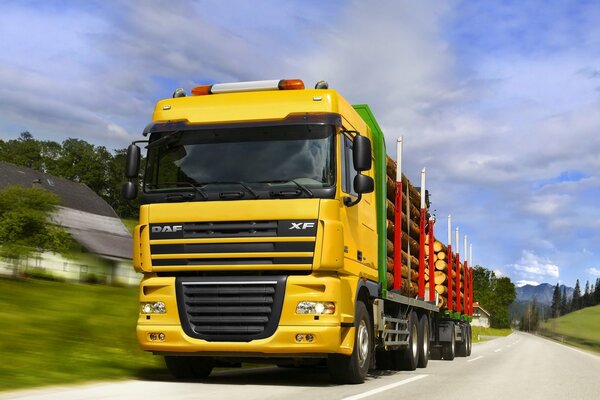 Большой жёлтый грузовик перевозит лес