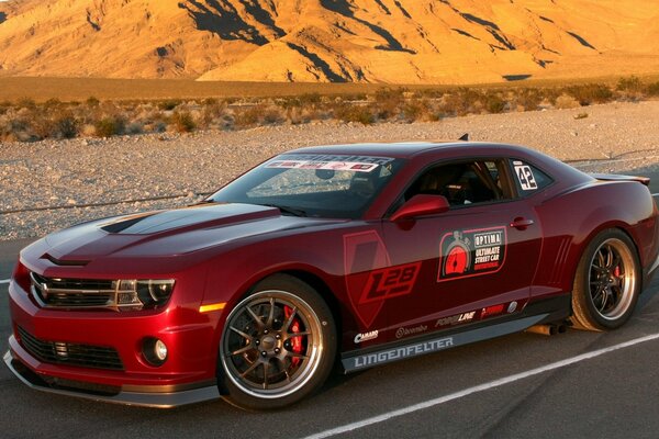 Against the background of the mountains, there is a red car on the road