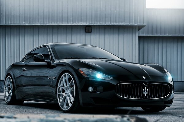 Black Maserati with headlights on