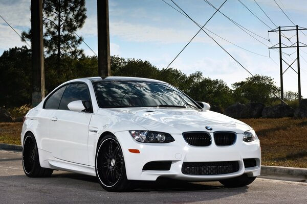 White BMW on the road on the background of transmission lines